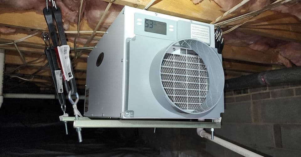 Dehumidifier installed in a basement with a digital display showing 53% humidity.