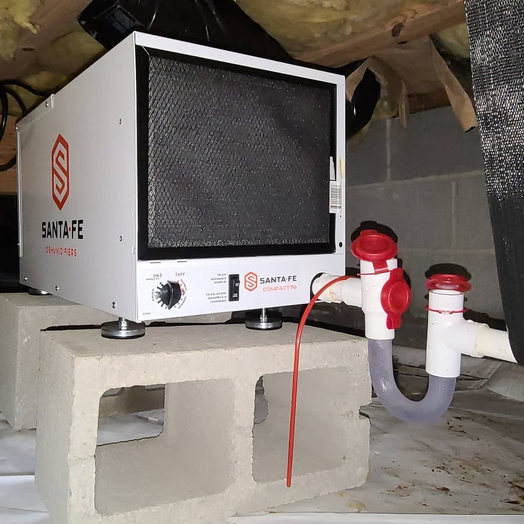 Santa Fe dehumidifier model in a basement setup with plumbing connections on display.