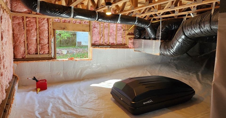 Renovated basement with exposed insulation, ventilation ducts, and a black storage unit.