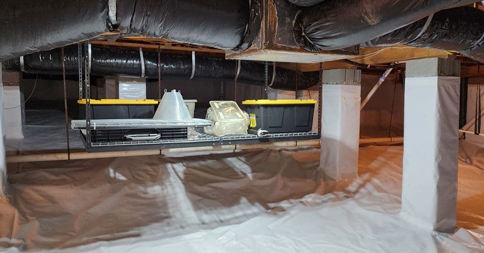 Basement storage area with organized bins, plastic sheeting, and ductwork above.