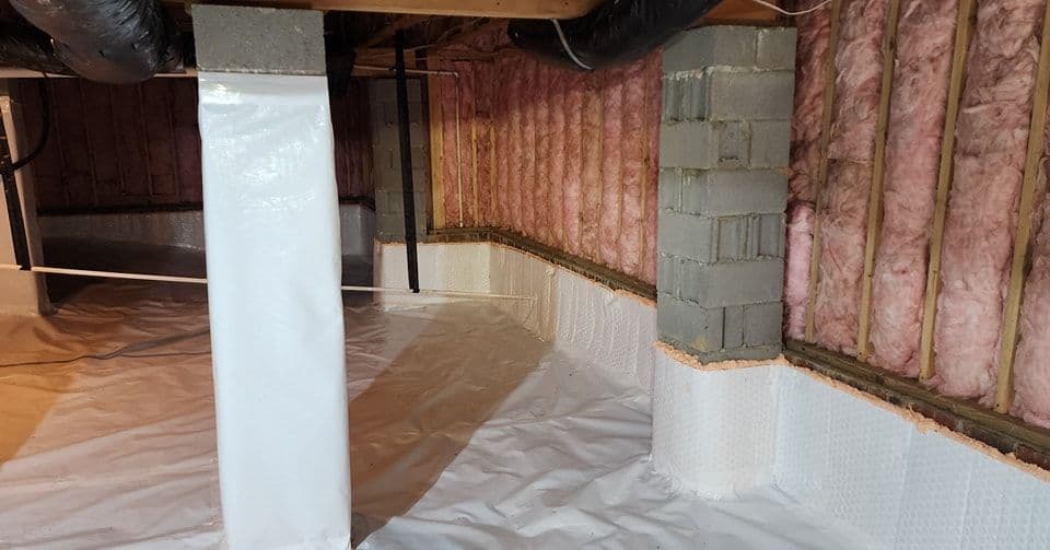 Clean, insulated basement with pink fiberglass insulation and waterproof wall barriers.