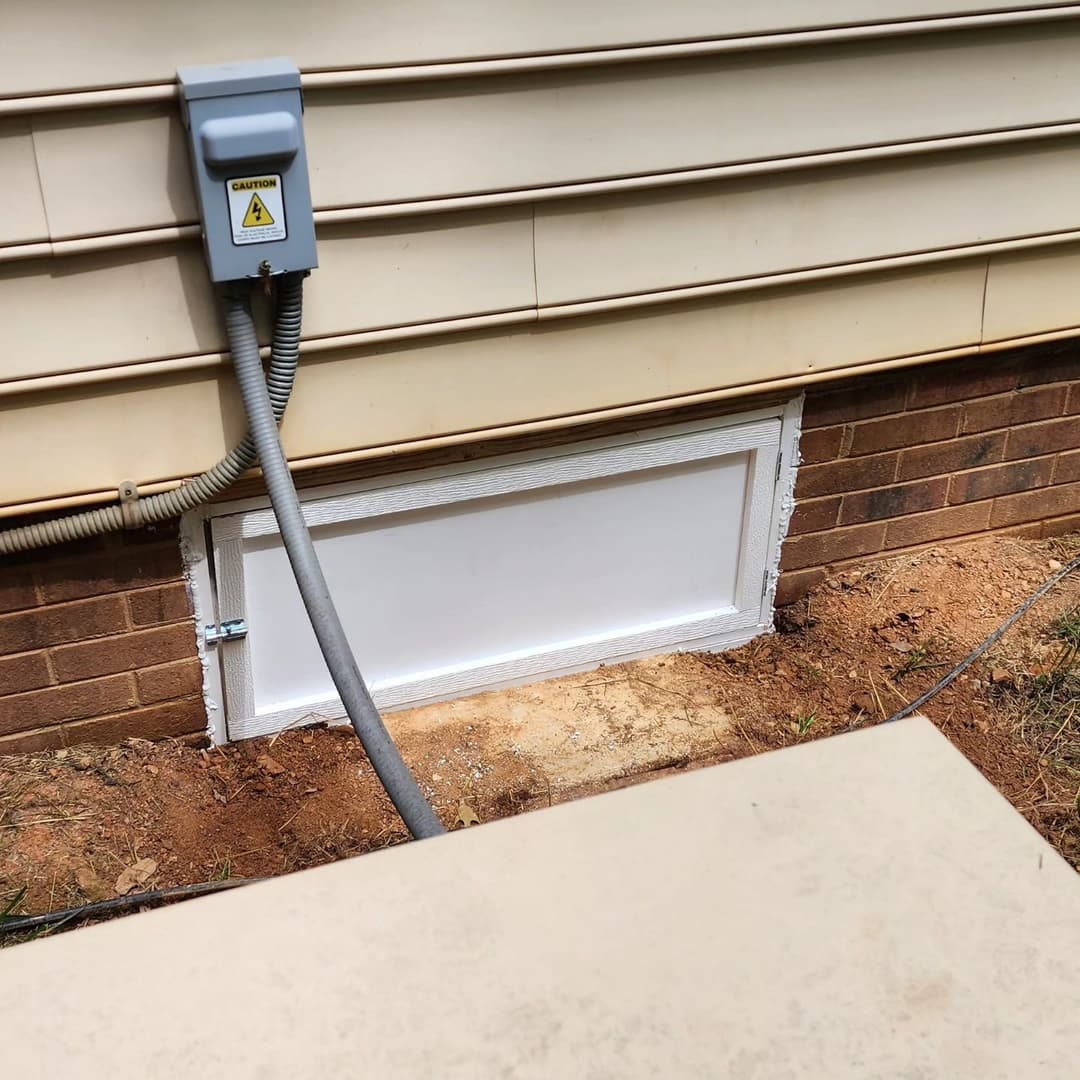 Exterior vent cover installation at home foundation with electrical connection visible.