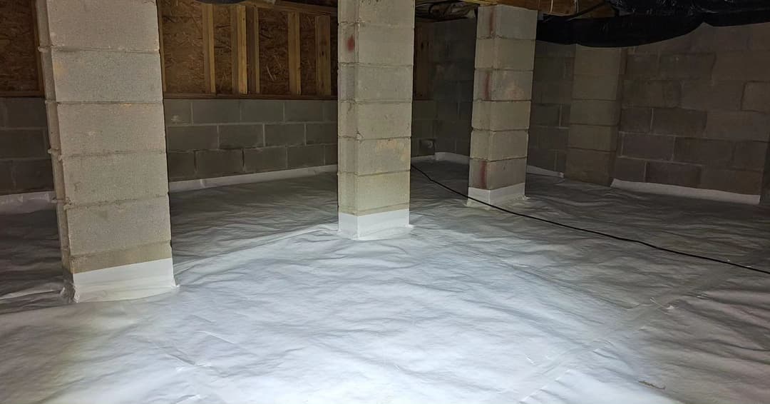 Clean, well-lit basement with concrete pillars and plastic sheeting on the floor.