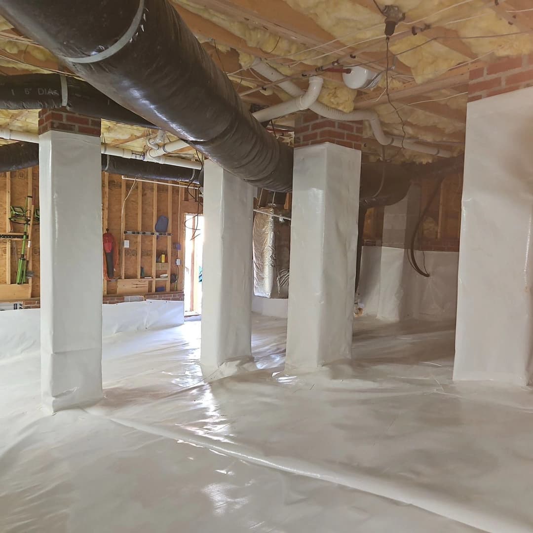 Finished basement with white polyethylene floor covering and insulated beams.