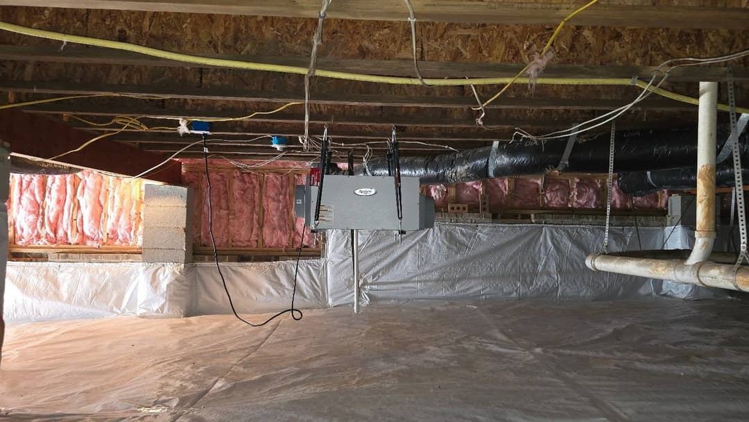 Crawl space with insulation, ductwork, and vapor barrier for moisture control.