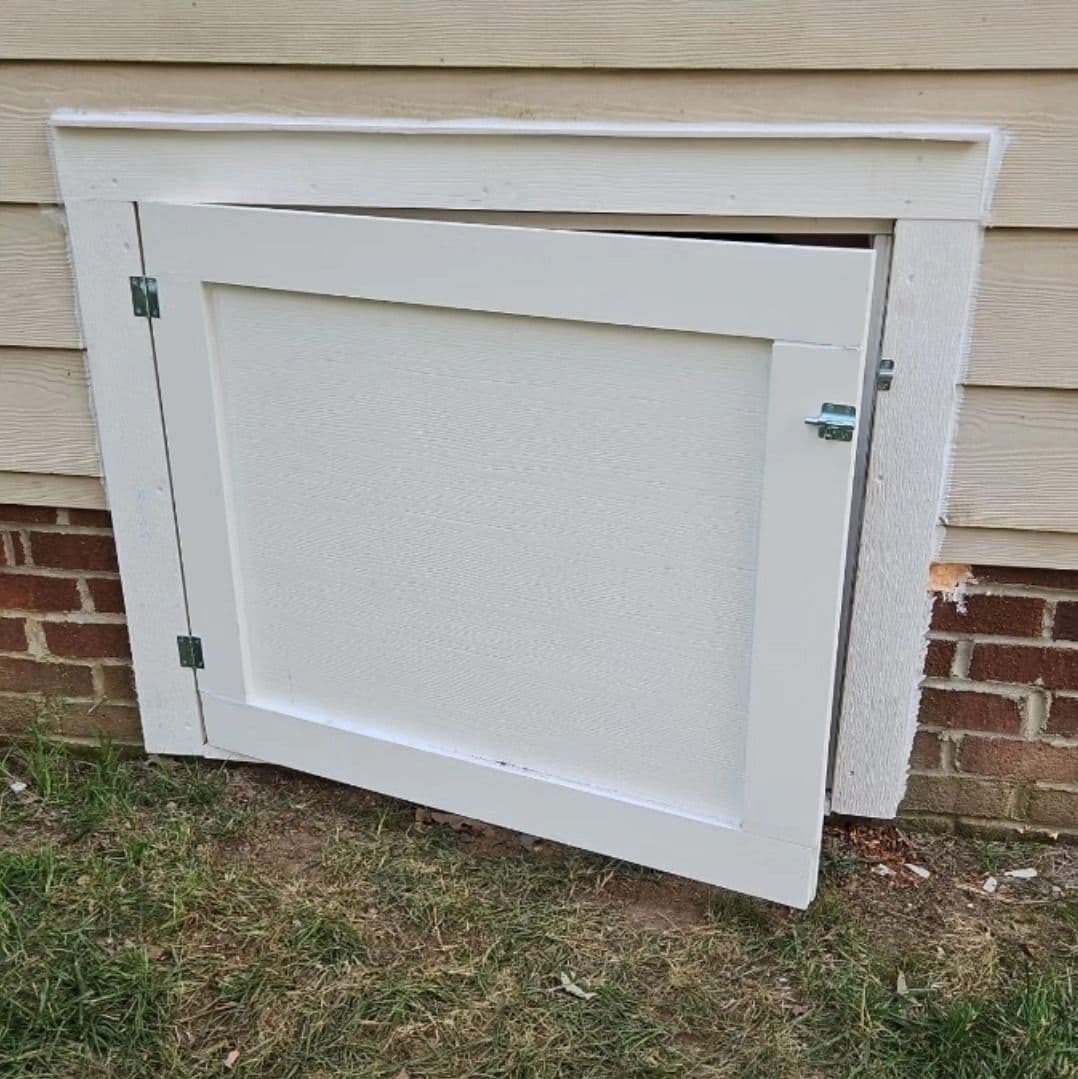 White access door installed on a brick wall, providing maintenance access to utilities.