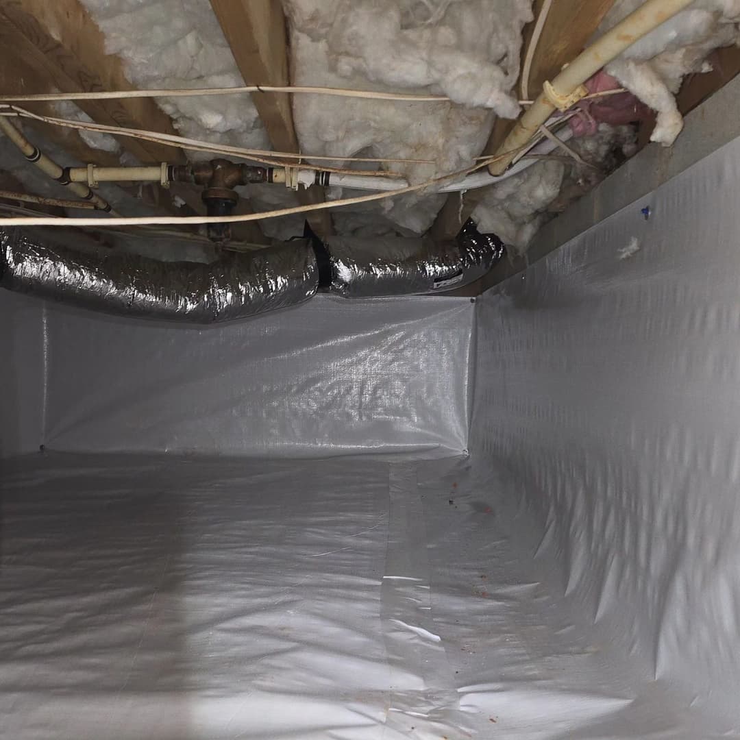 Crawl space with white polyethylene liner, insulation, and ductwork overhead.