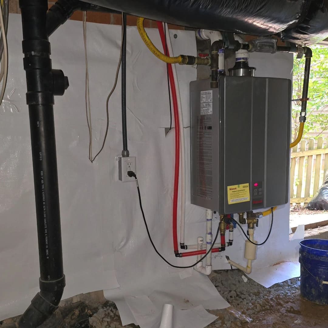 Tankless water heater installation in a basement with plumbing and drainage pipes visible.