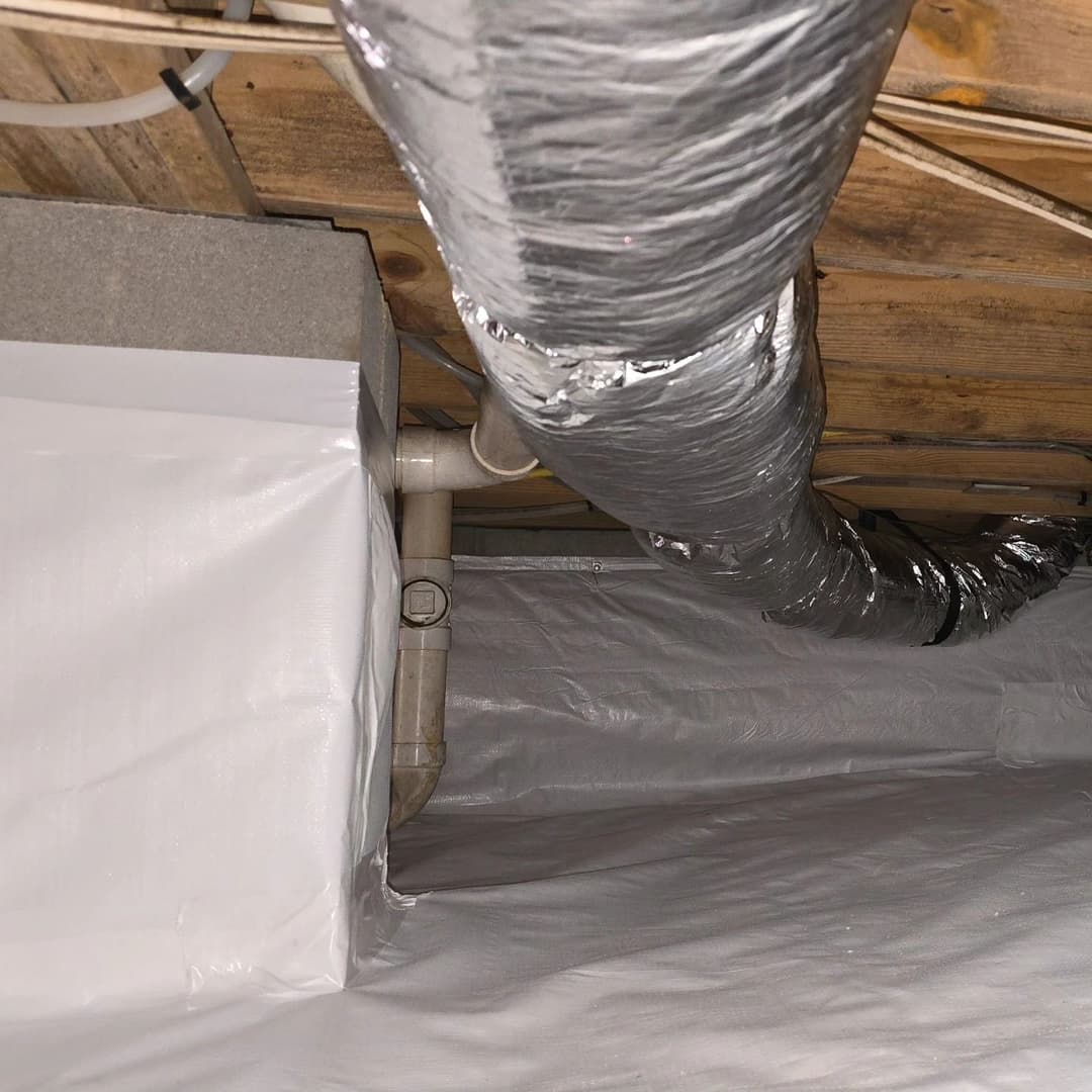 Insulated ductwork and piping under a basement ceiling with protective sheeting.