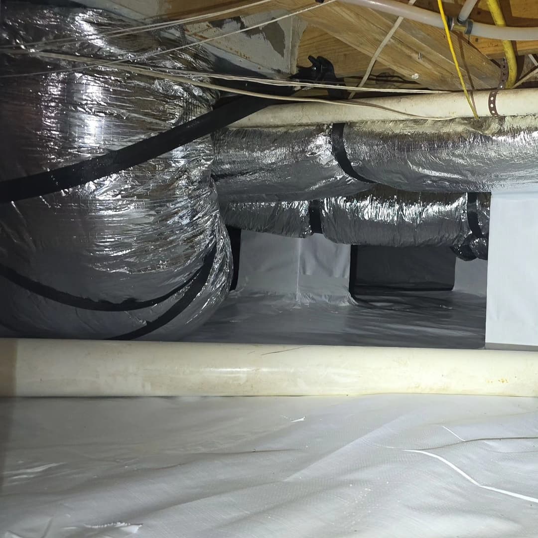 Insulated ductwork and vapor barrier in a residential crawl space for energy efficiency.