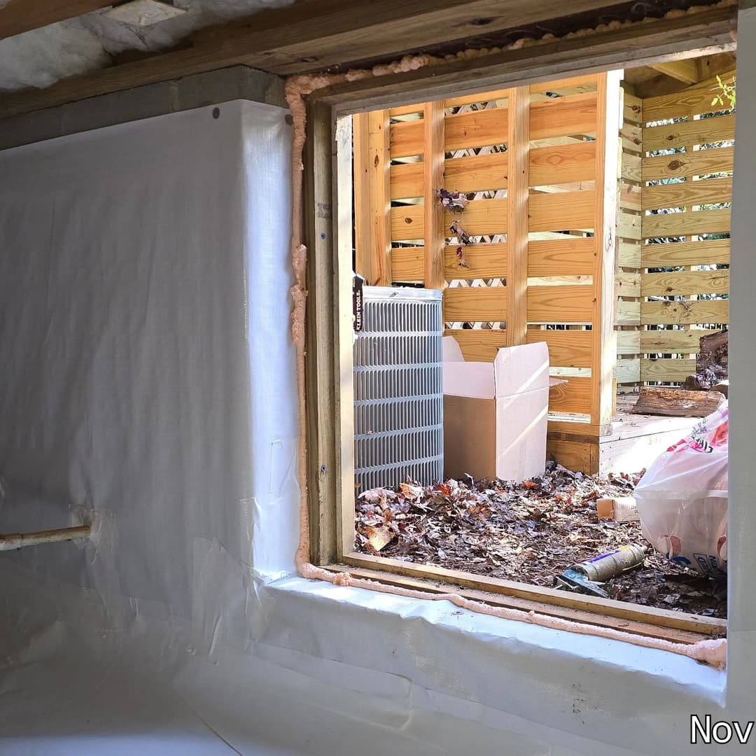 View of a window in a construction site with insulation and outdoor storage area visible.