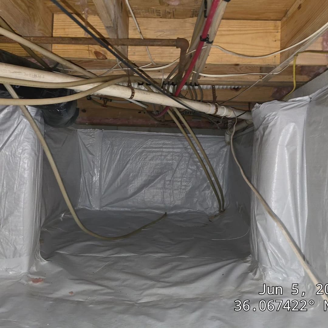 Crawl space with plastic lining and exposed pipes, ideal for home inspection context.