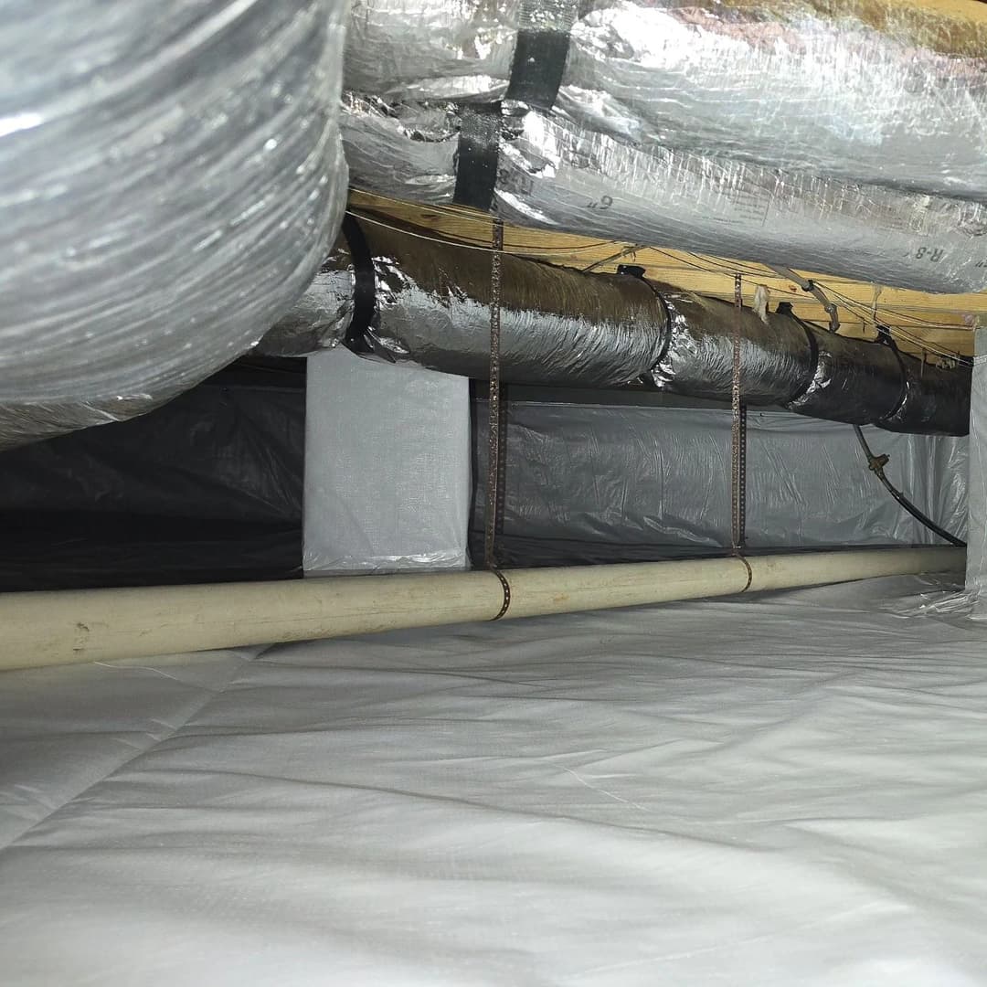 View of an insulated crawl space with ductwork and vapor barrier installation.